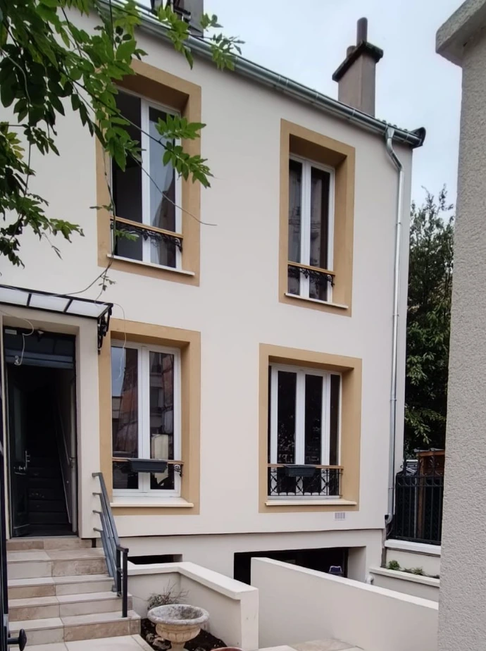 Rénovation de façade d'un bâtiment avec finition d'enduit et encadrements de fenêtres